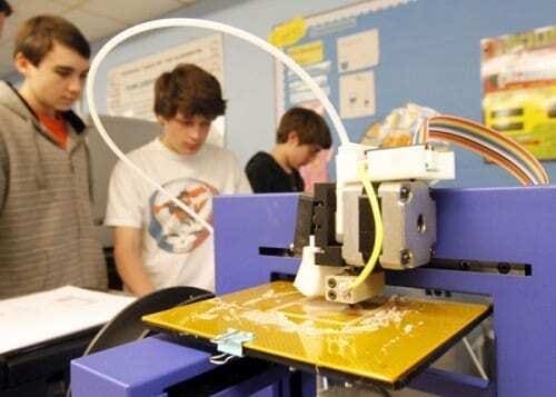 Alunos de escola observando impressora 3D funcionando dentro da sala de aula. Continue lendo nosso post!!